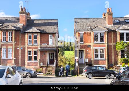 Un couple marchant sur un chemin / ruelle entre des rangées de maisons mitoyennes victoriennes sur une rue avec des champs verts en arrière-plan, Dorking, Surrey Angleterre Royaume-Uni Banque D'Images