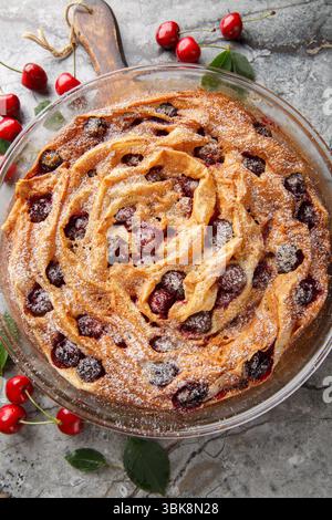 Tarte phyllo à la cerise Soufra avec crème anglaise à la vanille et sucre en poudre gros plan dans un bol en verre sur une planche de bois. Vue de dessus verticale Banque D'Images