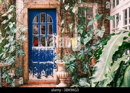 Extérieur style rustique de porte bleue avec fenêtres et plantes en pot dans le jardin Banque D'Images