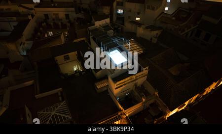 Vue aérienne d'une piscine sur le toit illuminée la nuit dans un cadre urbain. Banque D'Images