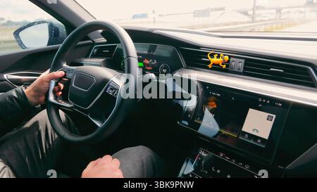 Les mains des conducteurs sur le volant dans la voiture moderne. Gros plan d'un conducteur mains sur le volant d'une voiture moderne, avec tableau de bord numérique visible et Banque D'Images