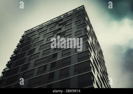 Bâtiment en verre avec prise de vue en angle de ciel nuageux foncé Banque D'Images