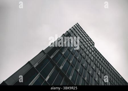 Bâtiment en verre avec prise de vue en angle de ciel nuageux foncé Banque D'Images