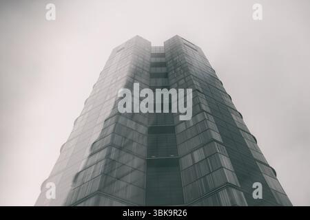 Bâtiment en verre avec prise de vue en angle de ciel nuageux foncé Banque D'Images