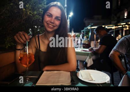Femme heureuse assise à table et appréciant boire en gros plan Banque D'Images
