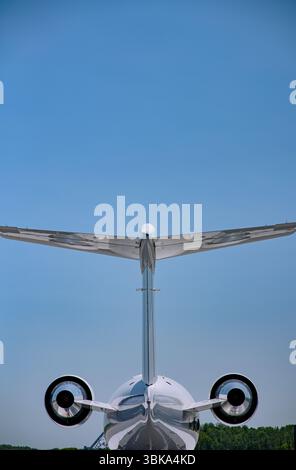 Vue arrière verticale d'un avion d'affaires sous un ciel bleu clair, montrant des bimoteurs et une queue en T avec symétrie par rapport à l'air libre. Banque D'Images