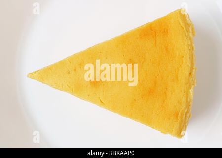 Vue de dessus d'une tranche de cheesecake cuit au four sur une assiette blanche Banque D'Images