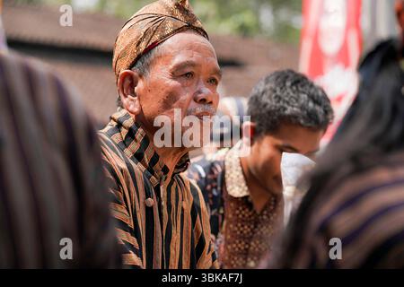 Un homme javanais âgé portant des lurik et blangkon traditionnels lors d'une procession culturelle dans le centre de Java, en Indonésie, exprimant calme et fierté Banque D'Images