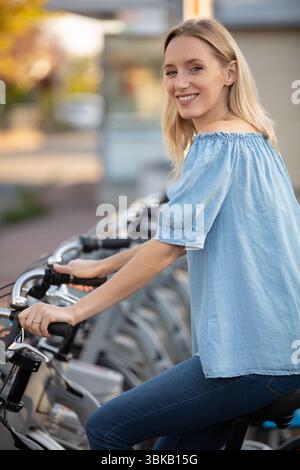 femme assise sur le vélo disponible à la location dans la ville Banque D'Images