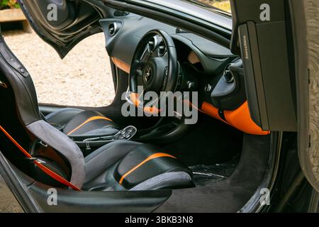 Vue intérieure d'une voiture de sport McLaren 570S de luxe avec sièges en cuir noir et orange, direction élégante et tableau de bord moderne Banque D'Images