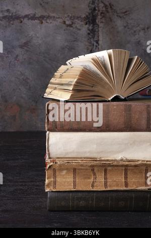 Un livre ouvert repose sur une pile de livres sur un fond brun Banque D'Images