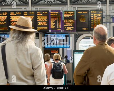 Londres , Royaume-Uni – 19 juin 2025 : Météo britannique. Les navetteurs de Paddington dans Summer Straw Hat, vérifiant les informations de départ du train sur la rangée de plusieurs écrans LED numériques, apprécient le temps chaud à travers le centre de Londres aujourd'hui - voyager vers et depuis le travail, rencontrer des amis, et tirer le meilleur parti de la première vague de chaleur majeure de la ville de l'année. La température devrait atteindre 34 °C ce week-end. Crédit : Glosszoom/Alamy Live News. Banque D'Images