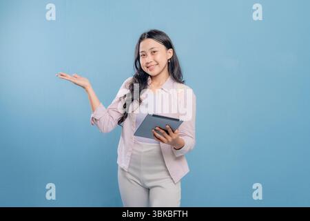 Une femme tient une tablette et pointe vers elle. Elle sourit et elle est heureuse Banque D'Images