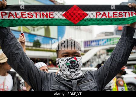 Un manifestant brandit une écharpe palestinienne pendant la manifestation. Une marche de solidarité pour Gaza a eu lieu à Bangkok. Organisé par la Palestine Solidarity Campaign (PSC), l'événement a rassemblé des manifestants appelant à un cessez-le-feu, à la fin du génocide, de l'apartheid et de l'occupation, et à l'accès de l'aide humanitaire à Gaza. Les participants portaient des drapeaux palestiniens et des pancartes avec divers messages de soutien. Banque D'Images