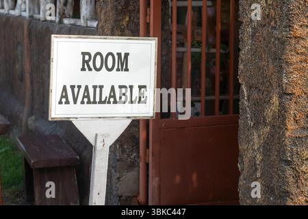 Panneau indiquant que la chambre disponible est sur un bâtiment. Le panneau est blanc et est sur un poteau en bois Banque D'Images