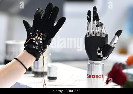 NANJING, CHINE - 20 JUIN 2025 - Un membre du personnel a commandé à distance un bras mécanique bionique de manière synchrone à l'aide de gants à détection de force lors de l'exposition universelle des semi-conducteurs 2025 à Nanjing, province du Jiangsu, Chine, le 20 juin 2025. Banque D'Images