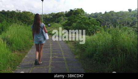 Femme marche à travers les rizières luxuriantes à ubud, bali, profitant du paysage paisible. Elle explore la nature, se sentant libre et aventureuse en asie du Sud-est Banque D'Images