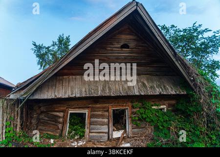 Une maison en bois en ruine. Village russe. Maison en bois envahie de plantes grimpantes. Photo de haute qualité Banque D'Images