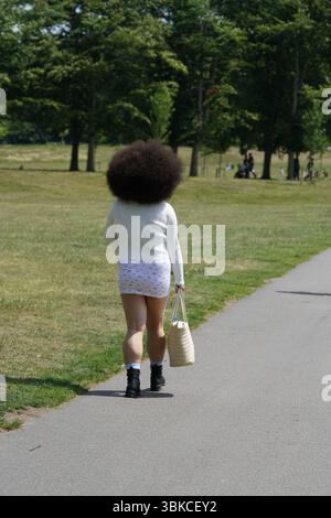 Vue arrière d'une femme marchant dans un parc en tenue d'été décontractée. Greenwich, Londres, Angleterre Banque D'Images