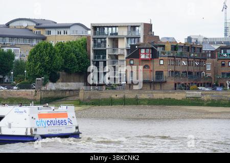 Appartements modernes en bord de rivière et croisière en bateau le long du front de mer de la ville. Greenwich, Londres, Angleterre Banque D'Images