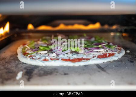 Pizza végétarienne fraîche cuisson dans le four à pizza à gaz Banque D'Images