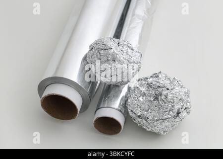 Rouleau de feuille d'aluminium avec des boules froissées sur fond blanc Banque D'Images