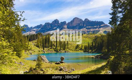 Le charmant lac Carezza avec ses eaux turquoises vibrantes, encadré par des forêts de pins luxuriantes et l'impressionnant groupe Rosengarten en arrière-plan UEDN Banque D'Images