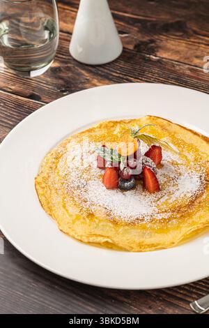 Crêpe fine garnie de sucre en poudre et de baies fraîches mélangées Banque D'Images