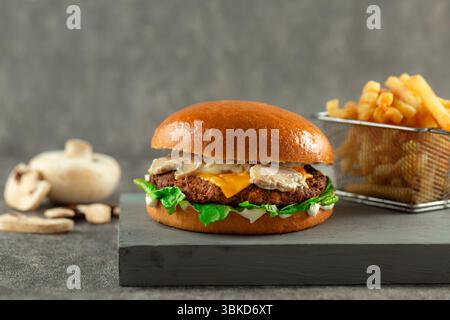 Hamburger aux champignons sauvages servi avec sauce aux champignons et frites. Banque D'Images