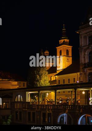 Le clocher et le dôme emblématiques de la cathédrale de produits Nicholas brillent chaleureusement la nuit à Ljubljana, en Slovénie. Banque D'Images