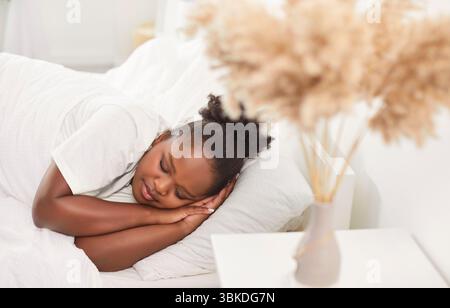 Dormir calme femme afro-américaine dans un lit confortable couché sur oreiller moelleux, paisible Banque D'Images