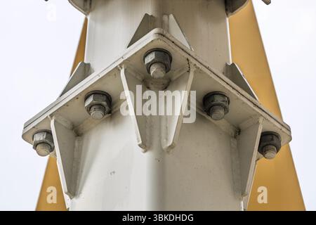 Plaque gousset boulonnée sur colonne en acier de construction avec poutre jaune, vue rapprochée de l'ingénierie Banque D'Images