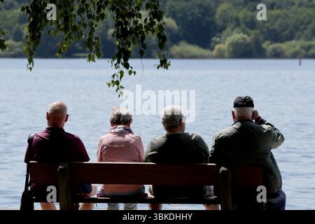 20 juin 2025, Mecklembourg-Poméranie occidentale, Waren (Müritz) : vacanciers et touristes assis sur des bancs sur les rives du Müritz par temps estival. Le temps ensoleillé domine la région des lacs de Mecklenburg. Photo : Bernd Wüstneck/dpa Banque D'Images