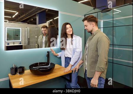 Couple heureux regardant les lavabos de salle de bains tout en magasinant pour des appareils de plomberie au magasin de bricolage Banque D'Images