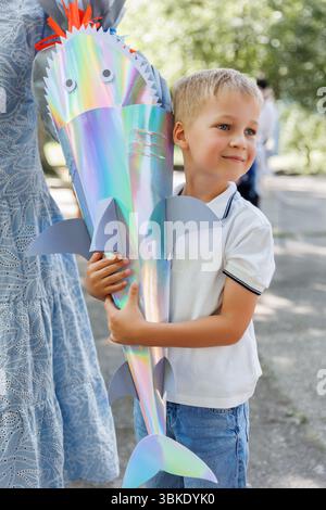 Smiling Boy tient Schultuete coloré en forme de requin rempli de cadeaux lors de son premier jour d'école en Allemagne. Cône brillant avec des ailerons et des yeux symbolise Banque D'Images