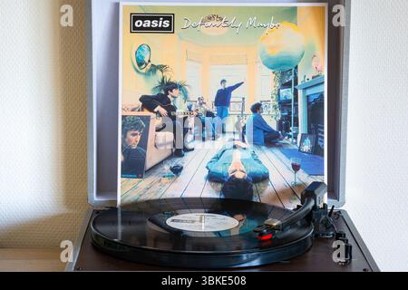 Tourne-disque avec disque de l'album ¨Definitety Maybe¨, du groupe de rock Oasis. Couverture de l'album en arrière-plan. Banque D'Images