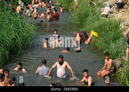 Srinagar, Inde. 20 juin 2025. Les gens se rafraîchissent dans un ruisseau pendant une chaude journée d'été dans la banlieue de Srinagar. De fortes vagues de chaleur balayent la vallée du Cachemire, poussant les températures à des sommets sans précédent dans plusieurs endroits. Le bureau météorologique local a conseillé aux résidents d’éviter les activités de plein air pendant les heures de pointe, de rester hydratés et de prendre les précautions nécessaires pour faire face à la canicule en cours. Crédit : SOPA images Limited/Alamy Live News Banque D'Images