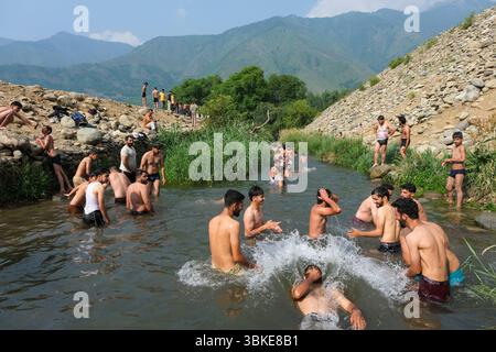 Srinagar, Inde. 20 juin 2025. Les gens se rafraîchissent dans un ruisseau pendant une chaude journée d'été dans la banlieue de Srinagar. De fortes vagues de chaleur balayent la vallée du Cachemire, poussant les températures à des sommets sans précédent dans plusieurs endroits. Le bureau météorologique local a conseillé aux résidents d’éviter les activités de plein air pendant les heures de pointe, de rester hydratés et de prendre les précautions nécessaires pour faire face à la canicule en cours. Crédit : SOPA images Limited/Alamy Live News Banque D'Images