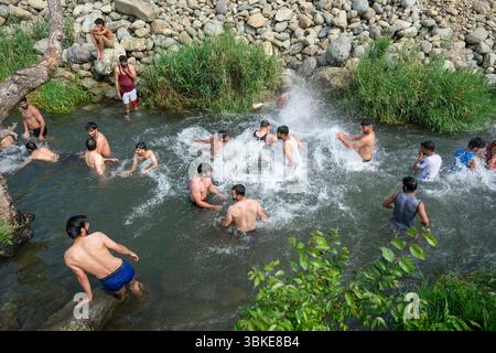 Srinagar, Inde. 20 juin 2025. Les gens se rafraîchissent dans un ruisseau pendant une chaude journée d'été dans la banlieue de Srinagar. De fortes vagues de chaleur balayent la vallée du Cachemire, poussant les températures à des sommets sans précédent dans plusieurs endroits. Le bureau météorologique local a conseillé aux résidents d’éviter les activités de plein air pendant les heures de pointe, de rester hydratés et de prendre les précautions nécessaires pour faire face à la canicule en cours. Crédit : SOPA images Limited/Alamy Live News Banque D'Images