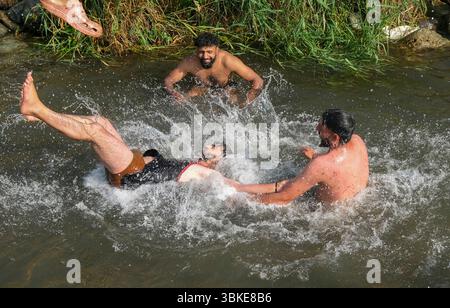 Srinagar, Inde. 20 juin 2025. Les gens se rafraîchissent dans un ruisseau pendant une chaude journée d'été dans la banlieue de Srinagar. De fortes vagues de chaleur balayent la vallée du Cachemire, poussant les températures à des sommets sans précédent dans plusieurs endroits. Le bureau météorologique local a conseillé aux résidents d’éviter les activités de plein air pendant les heures de pointe, de rester hydratés et de prendre les précautions nécessaires pour faire face à la canicule en cours. Crédit : SOPA images Limited/Alamy Live News Banque D'Images