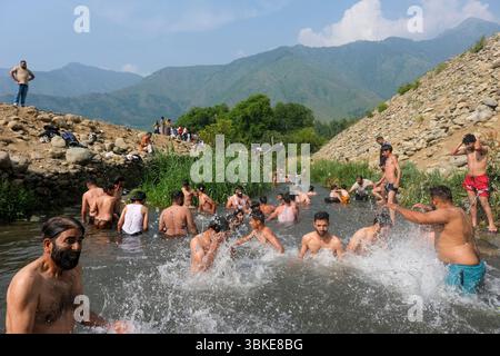 Srinagar, Inde. 20 juin 2025. Les gens se rafraîchissent dans un ruisseau pendant une chaude journée d'été dans la banlieue de Srinagar. De fortes vagues de chaleur balayent la vallée du Cachemire, poussant les températures à des sommets sans précédent dans plusieurs endroits. Le bureau météorologique local a conseillé aux résidents d’éviter les activités de plein air pendant les heures de pointe, de rester hydratés et de prendre les précautions nécessaires pour faire face à la canicule en cours. Crédit : SOPA images Limited/Alamy Live News Banque D'Images