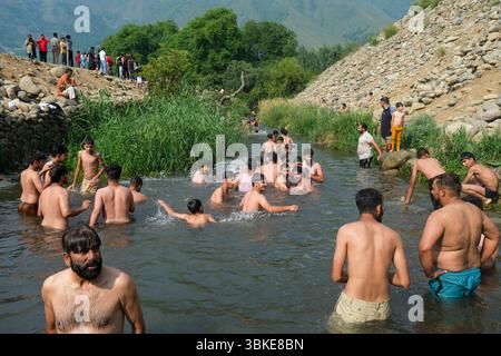 Srinagar, Inde. 20 juin 2025. Les gens se rafraîchissent dans un ruisseau pendant une chaude journée d'été dans la banlieue de Srinagar. De fortes vagues de chaleur balayent la vallée du Cachemire, poussant les températures à des sommets sans précédent dans plusieurs endroits. Le bureau météorologique local a conseillé aux résidents d’éviter les activités de plein air pendant les heures de pointe, de rester hydratés et de prendre les précautions nécessaires pour faire face à la canicule en cours. Crédit : SOPA images Limited/Alamy Live News Banque D'Images