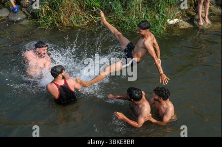 Srinagar, Inde. 20 juin 2025. Les gens se rafraîchissent dans un ruisseau pendant une chaude journée d'été dans la banlieue de Srinagar. De fortes vagues de chaleur balayent la vallée du Cachemire, poussant les températures à des sommets sans précédent dans plusieurs endroits. Le bureau météorologique local a conseillé aux résidents d’éviter les activités de plein air pendant les heures de pointe, de rester hydratés et de prendre les précautions nécessaires pour faire face à la canicule en cours. Crédit : SOPA images Limited/Alamy Live News Banque D'Images