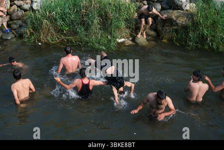 Srinagar, Inde. 20 juin 2025. Les gens se rafraîchissent dans un ruisseau pendant une chaude journée d'été dans la banlieue de Srinagar. De fortes vagues de chaleur balayent la vallée du Cachemire, poussant les températures à des sommets sans précédent dans plusieurs endroits. Le bureau météorologique local a conseillé aux résidents d’éviter les activités de plein air pendant les heures de pointe, de rester hydratés et de prendre les précautions nécessaires pour faire face à la canicule en cours. Crédit : SOPA images Limited/Alamy Live News Banque D'Images