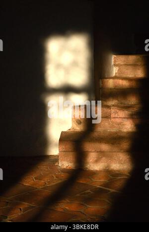 Fenêtre ombres sur un vieil escalier en briques dans une lumière chaude Banque D'Images