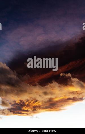 Un superbe spectacle de nuages au coucher du soleil met en valeur des couleurs orange vives et violettes profondes qui se décolorent dans le ciel nocturne. Banque D'Images