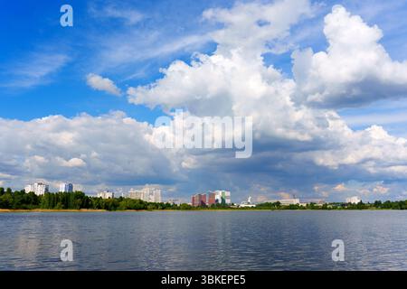 Photo grand angle de la ligne d'horizon urbaine avec des bâtiments reflétés dans le lac, avec des nuages spectaculaires et un ciel bleu clair. Banque D'Images