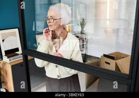 Femme caucasienne senior debout réfléchie dans le studio de retraite moderne Banque D'Images