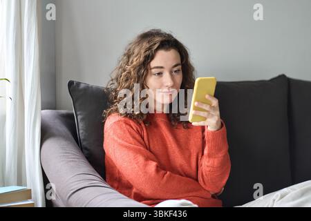 Jeune jolie femme tenant un téléphone portable à la maison. Banque D'Images