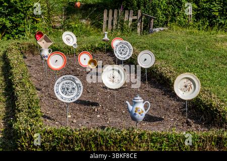 Plaques sur poteaux dans un jardin avant en France, Nouvelle-Aquitaine. Le motif correspond au proverbe allemand 'Über den Tellerrand schauen' (regardez au-delà du bord de votre assiette), qui fait référence à une attitude ouverte et curieuse dans laquelle on est prêt à transcender ses propres frontières et à apprendre de nouvelles choses. La phrase est souvent utilisée en relation avec le cosmopolitisme, un changement de perspective ou une innovation. Penser hors de la boîte. L'installation décorative de jardin comprend différentes pièces de vaisselle attachées à des bâtons et placées dans un parterre de fleurs pour créer une scène ludique et artistique. L'installation est Banque D'Images